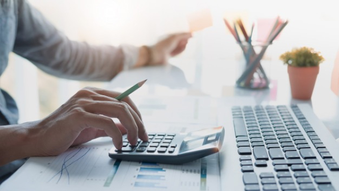 persona pie datora veic aprēķinus ar kalkulatoru