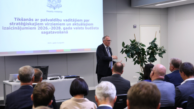 Vīrietis auditorijas priekšā uzstājas ar prezentāciju