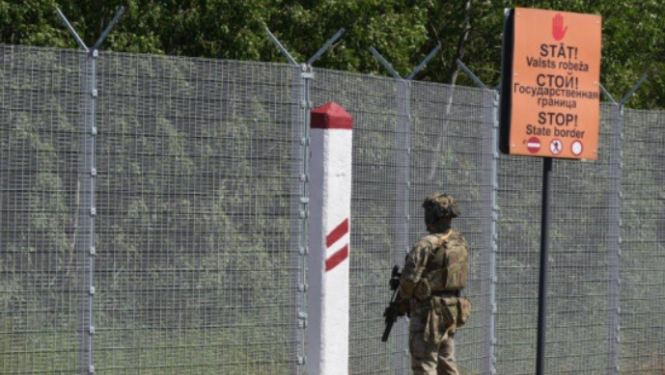 Valsts robeža ar brīdinošiem uzrakstiem un zemessargu no mugurpuses