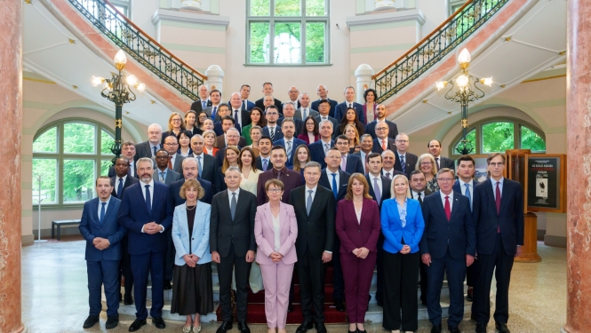 Uz Mākslas muzeja kāpnēm vairākās rindās stāv vīrieši un sievietes lietišķā apģērbā