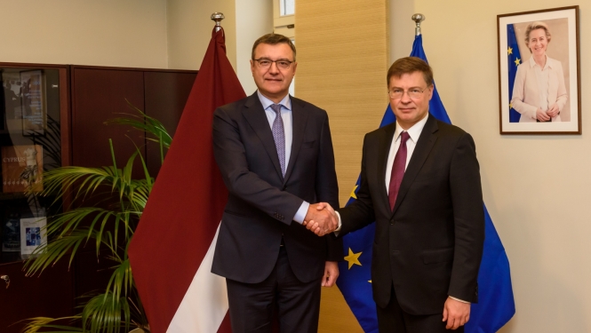 Divi vīrieši sarokojas uz Latvijas un ES karogu fona