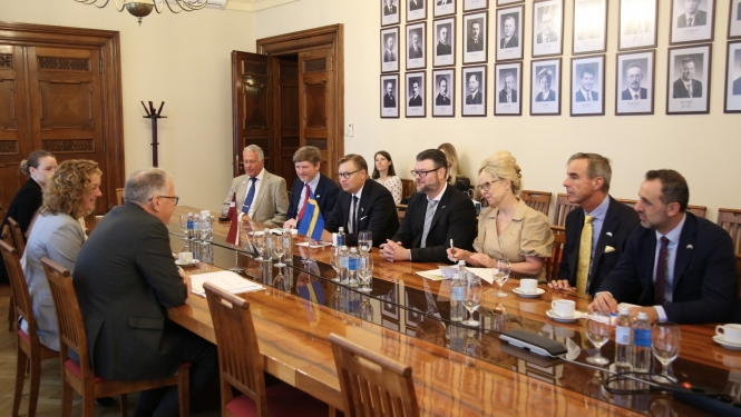 Abpus galdam sēž vīrieši un sievietes un diskutē