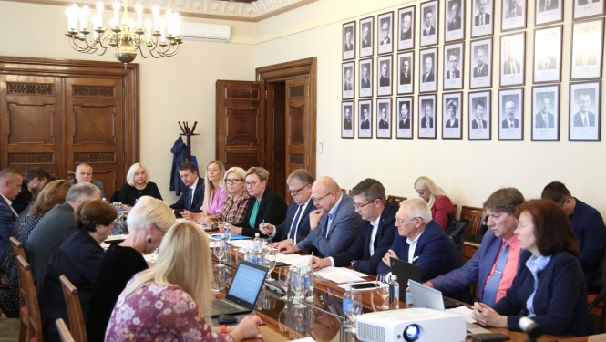 Sievietes un vīrieši sēž pie galda un diskutē