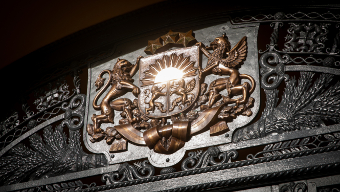 Attēlā redzams koka panelī izgrebts Latvijas ģerbonis