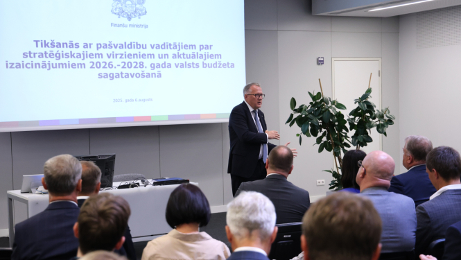 Vīrietis auditorijas priekšā uzstājas ar prezentāciju