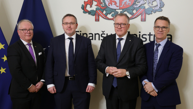 Attēlā redzami četri vīrieši tumšos uzvalkos un karogu un ģerboņa fona