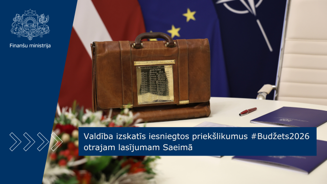 Attēlā redzams tradicionālais budžeta portfelis, kas novietots uz balta galda. Uz galda stāv arī ziedi un zilas dokumentu mapes. Fonā redzami Latvijas, ES un Nato karogi