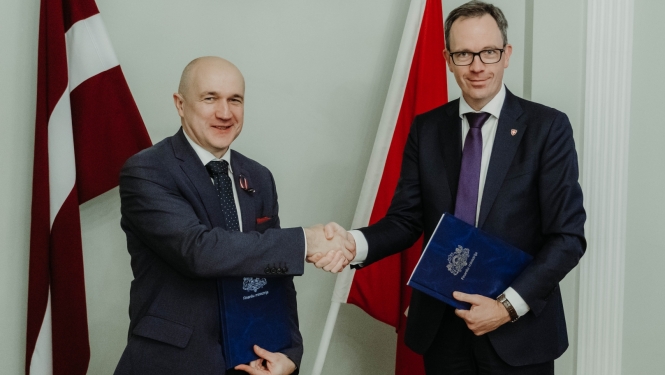 Divi vīrieši sarokojas uz Latvijas un Šveices karogu fona