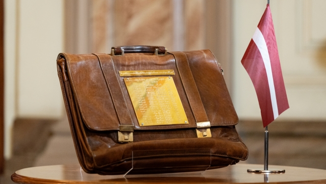 Budžeta portfelis uz galda līdzās Latvijas karogam