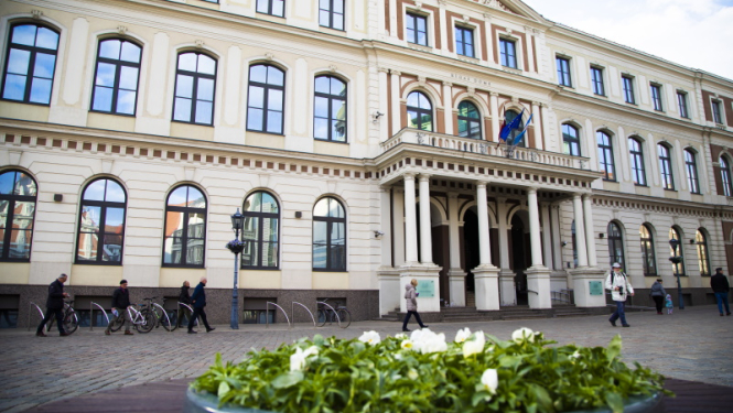 Attēlā Rīgas domes ēkas fasāde, foto priekšplānā ziedu kaste
