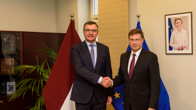 Divi vīrieši sarokojas uz Latvijas un ES karogu fona