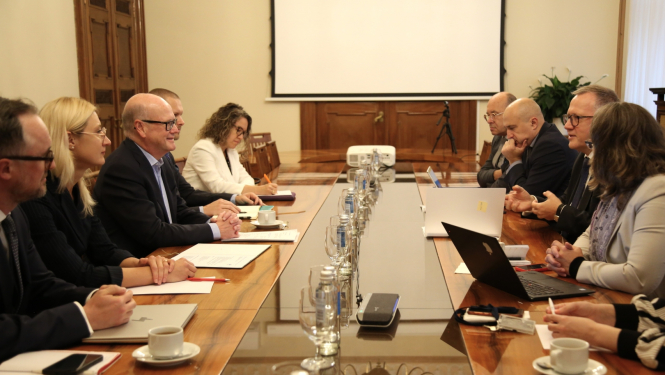 Abpus sēžu galdam sēž vīrieši un sievietes