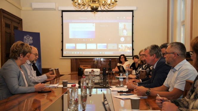 cilvēki sēž ap galdu, notiek diskusija