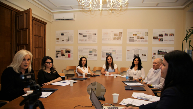 Cilvēki sēž pie apspriežu galda, sarunājas