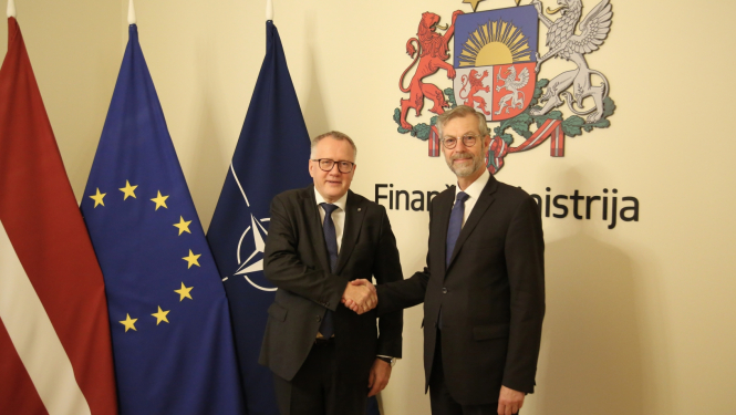 Divi vīrieši sarokojas uz Latvijas, ES un NATO karogu un ģērboņa fona