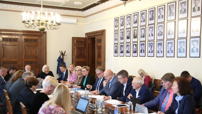 Sievietes un vīrieši sēž pie galda un diskutē