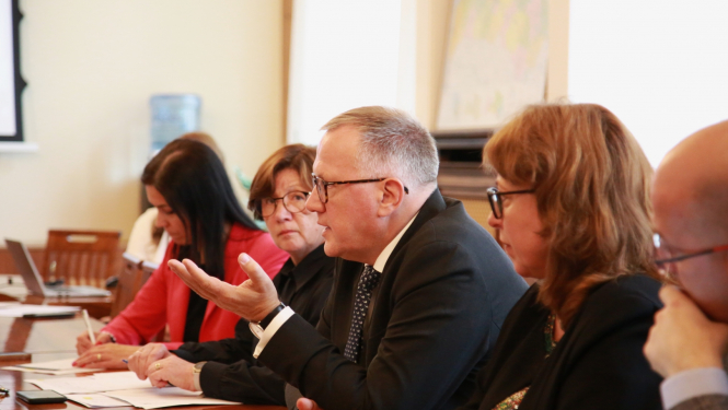 Cilvēki rindā sēž pie galda