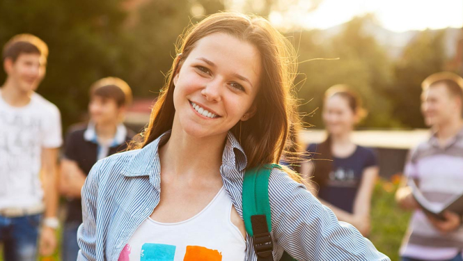 Smaidīga meitene ar zaļu mugursomu skatās kamerā