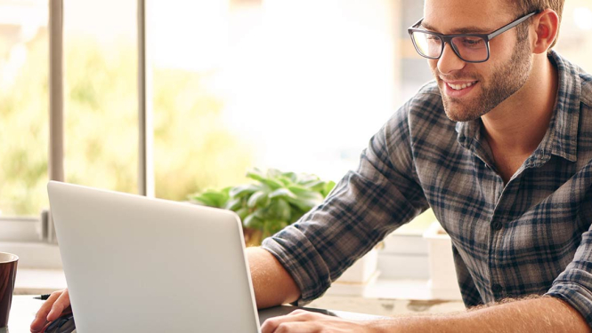 Vīrietis ar brillēm strādā ar datoru