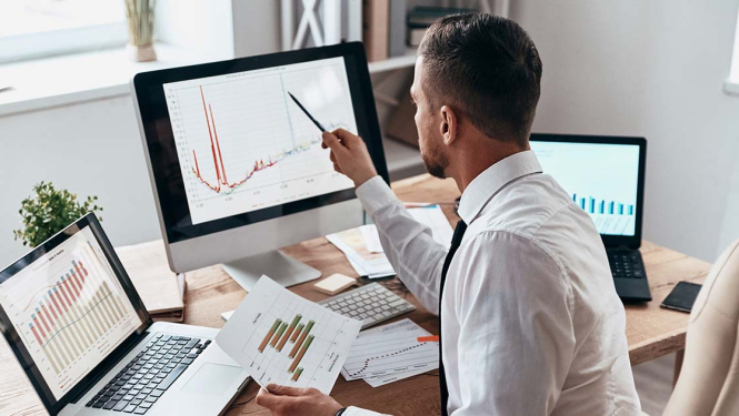 Vīrietis ar roku rāda uz grafikiem datorā