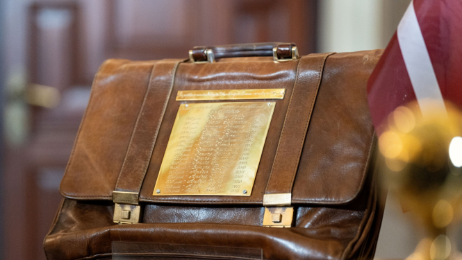 Budžeta portgelis tuvplānā uz galda līdzās Latvijas karogam