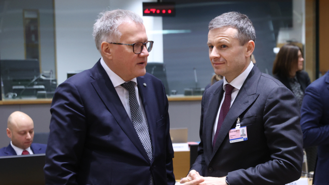 Divi vīrieši stāv viens pret otru un sarunājas