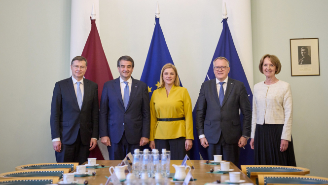 Attēlā redzami pieci cilvēki stāvam rindā uz karogu fona