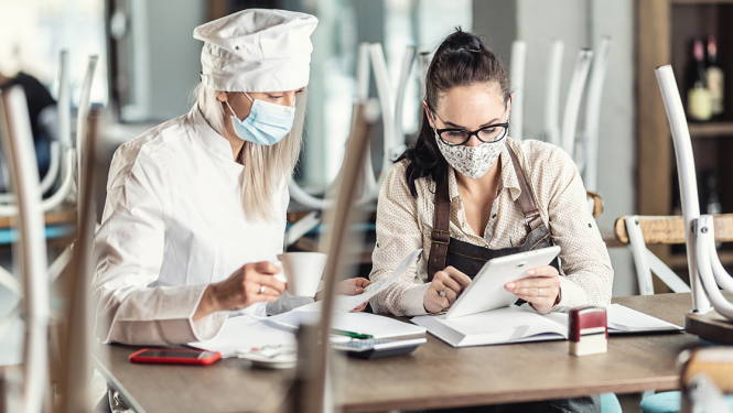 Kafejnīcā divi darbinieki skatās planšetē