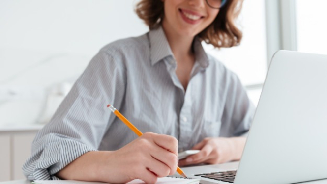 Sieviete pie datora un pierakstu blociņa