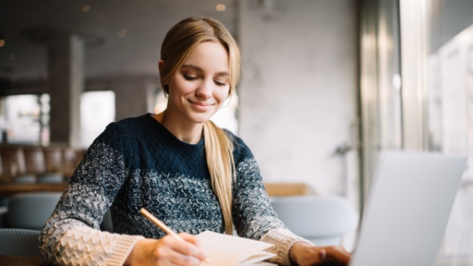 Meitene pie portatīvā datora mācās, veic pierakstus