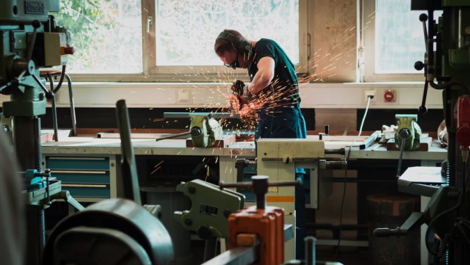 Vīrietis veic apstrādes darbus rūpnīcā