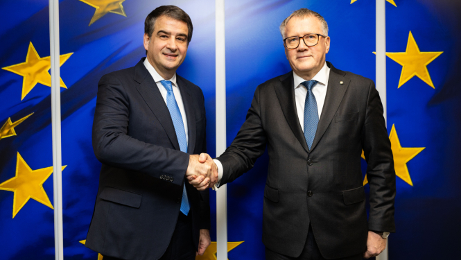 Finanšu ministrs Arvils Ašeradens un Kohēzijas komisārs Rafaēls Fito sarokojas un ES karoga fona 