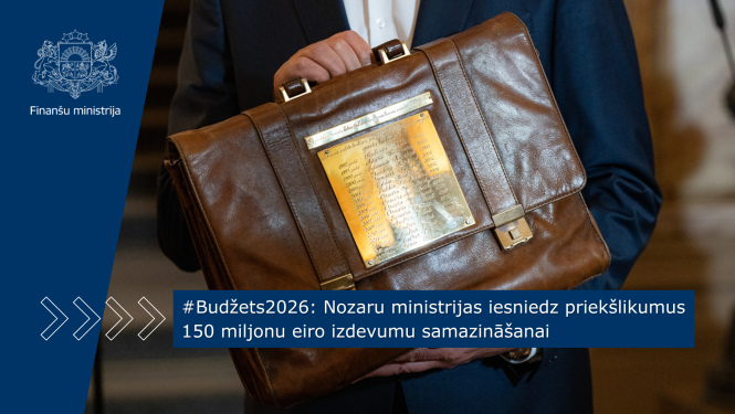 Vīrietis zilā uzvalkā tur rokās paceltu budžeta portfeli uz kura ir plāksne at iegravētiem ministru vārdiem, kuri nesuši portfeli uz Saeimu