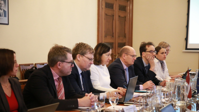 Cilvēki rindā sēž pie apspriežu galda