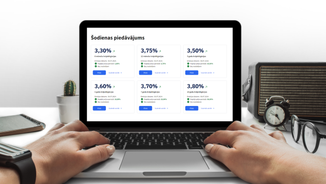 Tuvplānā redzams portatīvais dators un sievietes rokas, kuras spiež klaviatūru