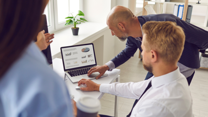 vairāki cilvēki, kuri redzami ni mugurpuses, skatās datora ekrānā