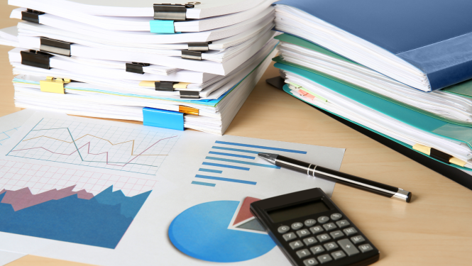 Dokumentu mapes, papīra lapa ar grafikiem, pildspalva un lupa uz galda