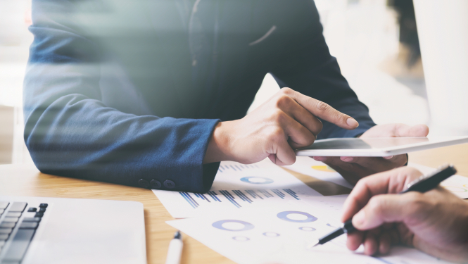 grafiki un vīrieša roka rāda uz planšetdatoru