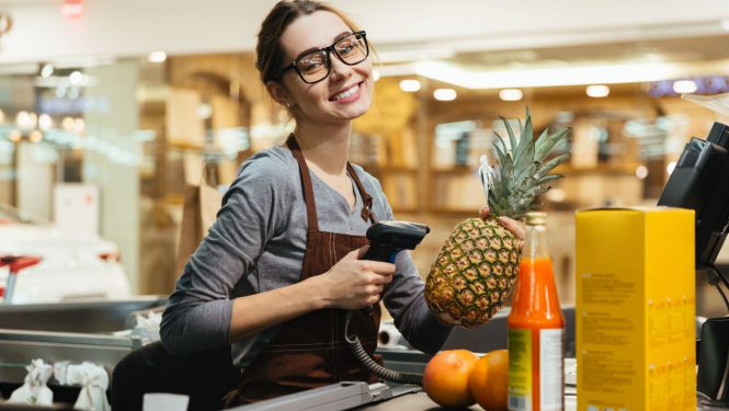 Skolniece strādā pie kases veikalā