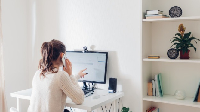 sieviete skatās datorā un runā pa telefonu