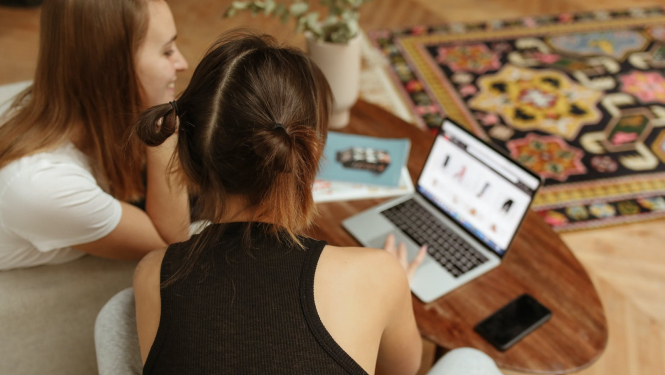 Meitene un sieviete iepērkas internetā, skatoties datora ekrānā