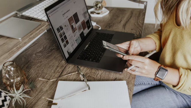 sieviete pie datora ar telefonu