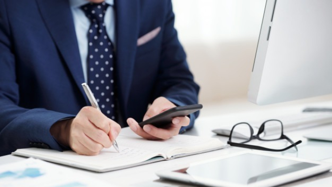 vīrietis uzvalkā pie darba galda