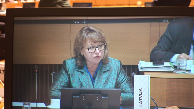 Attēlā redzama sieviete, kura uzstājas konferencē ar uzrunu