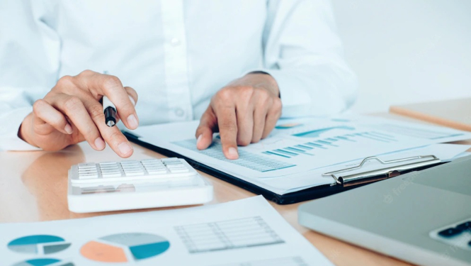 cilvēks pie galda ar dokumentiem, grafikiem