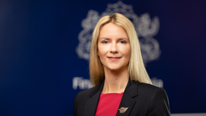 Olgas Bogdanovas portrets uz tumši zila fona ar finanšu ministrijas ģērboni