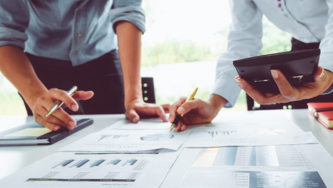 Vīrietis un sieviete pie galda ar dokumentiem veic aprēķinus