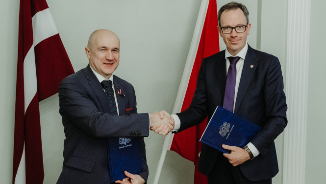 Divi vīrieši sarokojas uz Latvijas un Šveices karogu fona