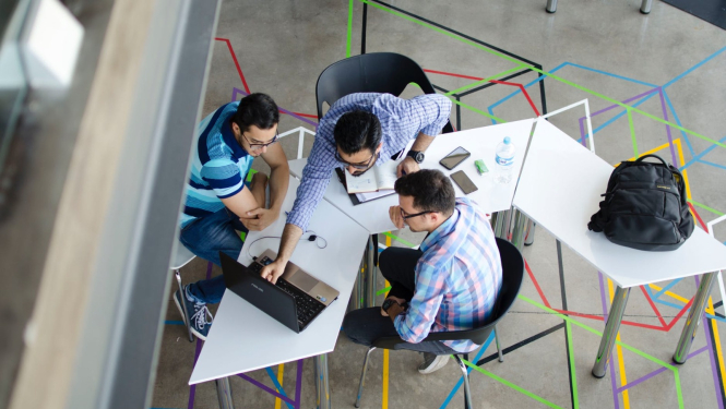 Trīs vīrieši strādā pie projekta, skatās datorā