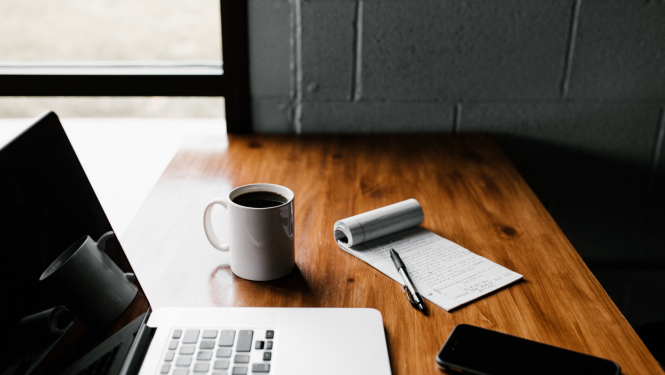 darba galds ar portatīvo datoru, krūzi, piezīmju bloku